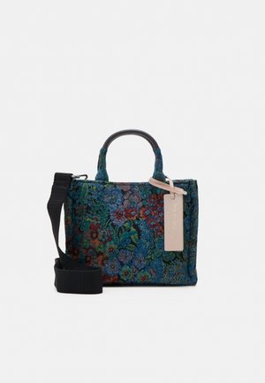 Petit sac à main rectangulaire avec motif de tapisserie florale dans des tons bleus et verts, sangle noire et étiquette beige attachée à la poignée.