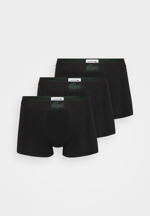 Trois paires de boxers noirs en tissu doux, avec des ceintures élastiques noires ornées d'un logo vert. Design simple, sans motifs.