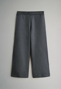 Tmavo šedé tepláky po lýtka s elastickým pásom. Hladká textúra, jednoduchý dizajn a bez viditeľných vzorov alebo hardvérových detailov.