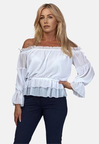Biała bluzka z odkrytymi ramionami, z falbanką przy dekolcie i mankietach rękawów, z marszczoną talią oraz lekkim, zwiewnym materiałem.