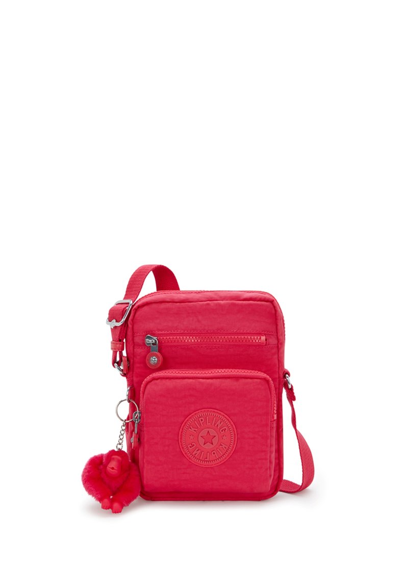 Röd nylonaxelväska med justerbar rem, två zippered fack och rund logobadge. Inkluderar en fluffig apa nyckelring.