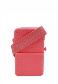 Borsa in silicone rosa con superficie testurizzata e ampia tracolla che presenta il logo "havaianas". Forma rettangolare compatta con chiusura a zip.