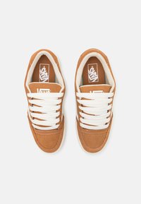 Brune semskede sneakers med hvite snøringer og gummisåler. Har en polstret krage og en logo på tungen og siden. Klassisk design.