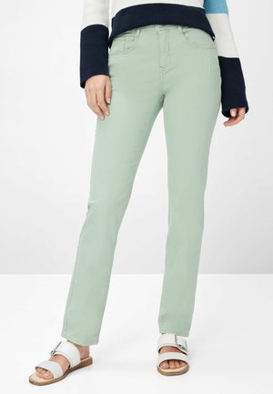 Hellgrüne, gerade geschnittene Hose mit mittelhoher Taille, ausgestattet mit Gürtelschlaufen und vorderen Taschen. Kombiniert mit weißen Rutsch-Sandalen.