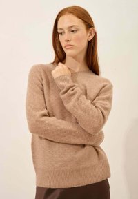 Lichtbruin gebreid sweater met een ronde halslijn, geribbelde mouwen en zoom, gemaakt van een zachte, gestructureerde stof.