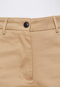 Pantaloni khaki con chiusura a bottone, caratterizzati da un tessuto liscio, dettagli cuciti e un design pulito delle tasche anteriori.