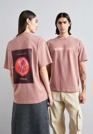 Roosa puuvillane T-särk, mille seljal on graafiline punane planeet mustade ja valgete tekstidega. Ees on helesinise logoprint.
