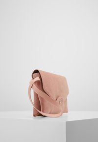 Borsa a spalla in suede rosa con design piatto, patta superiore curvata e una sola tracolla. Presenta una chiusura a scatto e una texture liscia.