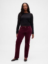 Haut noir à manches longues avec un col rond, associé à un pantalon en velours côtelé bordeaux avec poches avant et coupe droite.