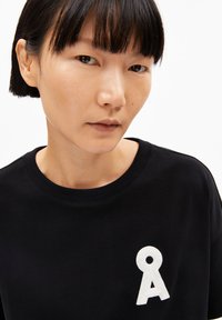 Black cotton sweatshirt featuring a round neck and a white embroidered logo on the left chest. Smooth texture with a relaxed fit.
