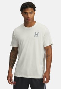 White cotton t-shirt featuring a navy graphic logo on the left chest. Short sleeves, round neckline, and a relaxed fit.