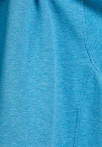 Lichtblauwe stof met een zachte textuur, gekenmerkt door een gemêleerd patroon. Eenvoudig ontwerp met zichtbare naden en zonder verdere accenten.