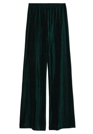 Person wearing dark green pleated wide-leg pants and matching short-sleeve top, holding a small black handbag, standing on neutral floor.