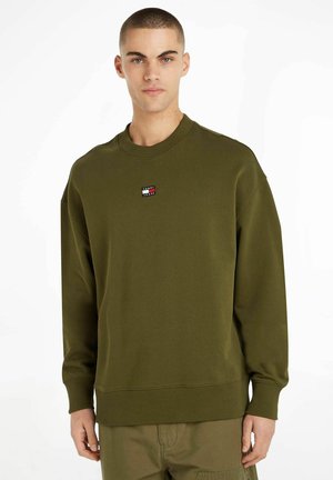 Sudadera verde oliva hecha de una mezcla de algodón. Presenta un cuello redondo, puños acanalados y un pequeño parche con el logo en el pecho.
