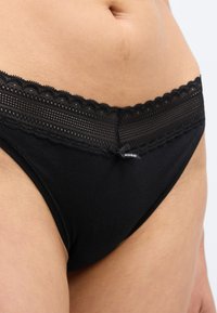 Chiloți negri din bumbac cu talie bordată cu dantelă, având un model cu puncte și un mic detaliu cu fundă. Materialul este neted și elastic.