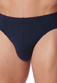 Slip di cotone blu navy con design a vita bassa, caratterizzato da una texture liscia, cuciture rinforzate e una parte anteriore sagomata per supporto.