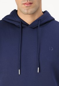 Navy blue hoodie made of soft fabric with a front pocket. Features a drawstring hood and subtle embossed logo on the chest.