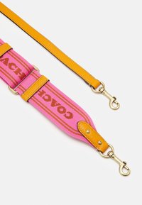 Plátěný popruh na rameno v růžové a oranžové barvě, s nápisem "COACH" v hnědé. Zlacené kování a kožené detaily dokončují design.