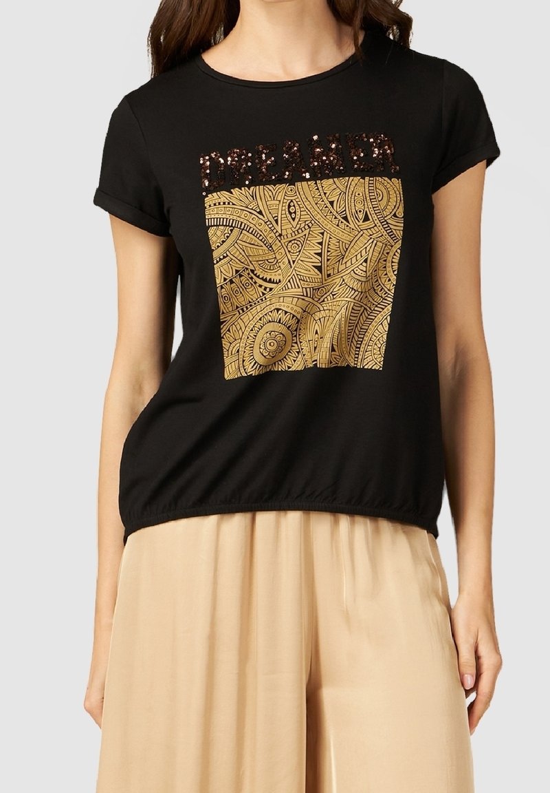 T-shirt noir à manches courtes avec un motif géométrique doré et un texte "DREAMER" scintillant ; tissu doux avec un détail de bas froncé.