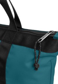 Tyrkysová a černá taška přes rameno s texturovanou tkaninou, dvojitými krátkými uchy a zipovým uzávěrem se stříbrným kovovým táhlem.