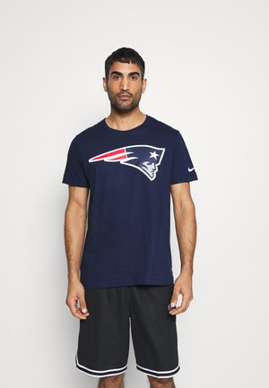 Camiseta de algodón azul marino con un gran logotipo blanco y rojo en el pecho. Combinada con pantalones cortos negros con ribetes blancos.