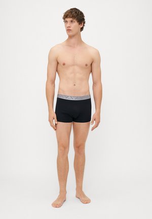 Černé boxerky s širokým šedým páskem se jemným vzorem. Materiál je hladký a design poskytuje úzký střih.