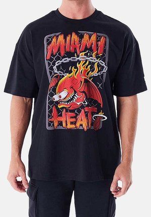 T-shirt noir avec une créature dessin animé enflammée dribblant un ballon de basket, texte indiquant "Miami Heat" en lettres style flammes.