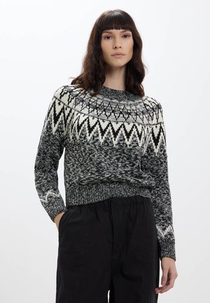 Maglione a maglia in bianco e nero con motivo geometrico sulla spalla. Presenta maniche lunghe, polsini a coste e orlo aderente. Realizzato in tessuto testurizzato.