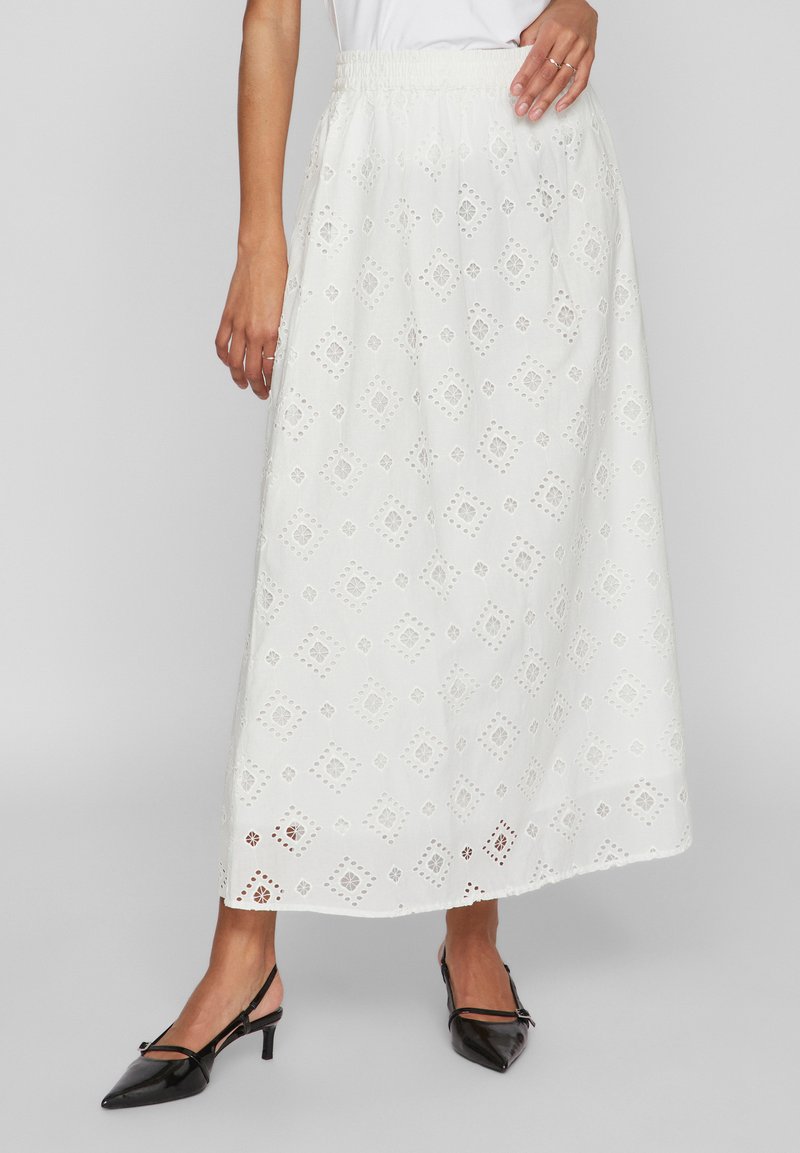 Λευκή μάξι φούστα με κεντημένα σχέδια από οπές, ελαστική μέση και ρομαντική γραμμή. Συνδυασμένη με μαύρες μυτερές μπαλαρίνες.