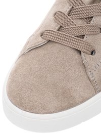 Beige suede sneaker toe with thick woven laces and white rubber sole, showing texture and stitching details.