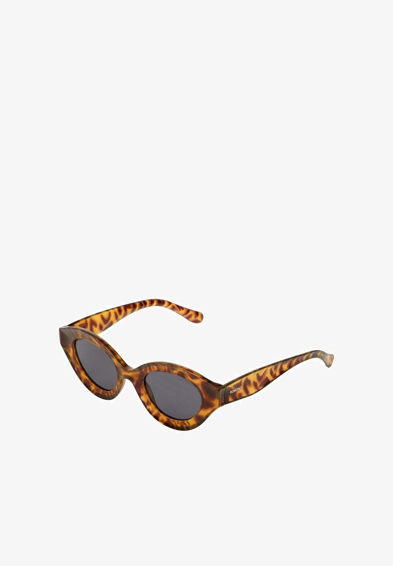 Gafas de sol de carey con forma de ojo de gato, que cuentan con lentes oscuros y patillas texturizadas con un sutil patrón de print animal.