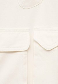 Witte spijkerjacket met een gestructureerd ontwerp, voorzien van twee voorzakken met kleppen en een gestikte textuur.