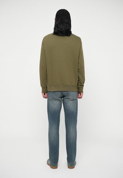 Sweatshirt vert olive avec un col rond, une bordure côtelée et des poignets, associé à un jean bleu et des chaussures marron, vu de dos.