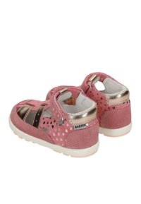 Sandales en daim rose pour tout-petit avec découpes en forme de cœur, accents en or rose métallique, semelle blanche et fermeture à bride Velcro.