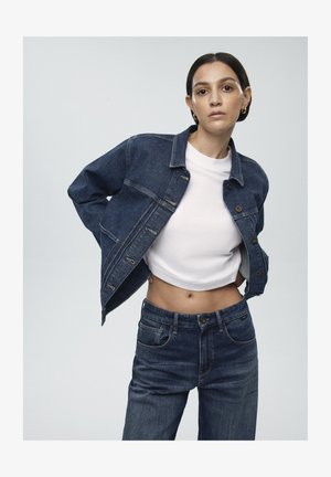 Dark blue denim jacket with a cropped fit, button closure, and chest pockets, paired with high-waisted dark jeans and a white cropped t-shirt.
