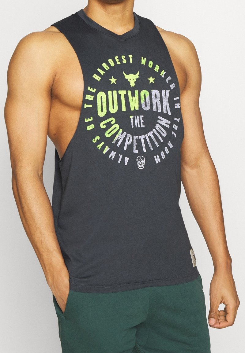 Camiseta sin mangas de color gris oscuro con texto multicolor en negrita que dice "SUPERA A LA COMPETENCIA", con un logo de toro y costuras en contraste.