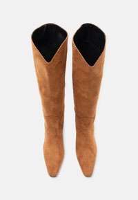 Καφέ σουέτ μπότες μέχρι το γόνατο με μυτερή μύτη, με άνοιγμα σε σχήμα V στην κορυφή και διακριτικές ραφές στον άξονα.
