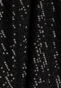 Tissu noir dense recouvert de petites paillettes argentées brillantes alignées en motifs verticaux et diagonaux.