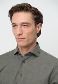 Grijze button-up shirt in een gestructureerde stof met een kraag en zwarte knopen, met een schone, op maat gemaakte uitstraling.