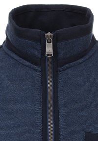 Giacca zip-up blu notte con colletto alto, texture a maglia, accenti scuri a contrasto e zip in metallo argentato.