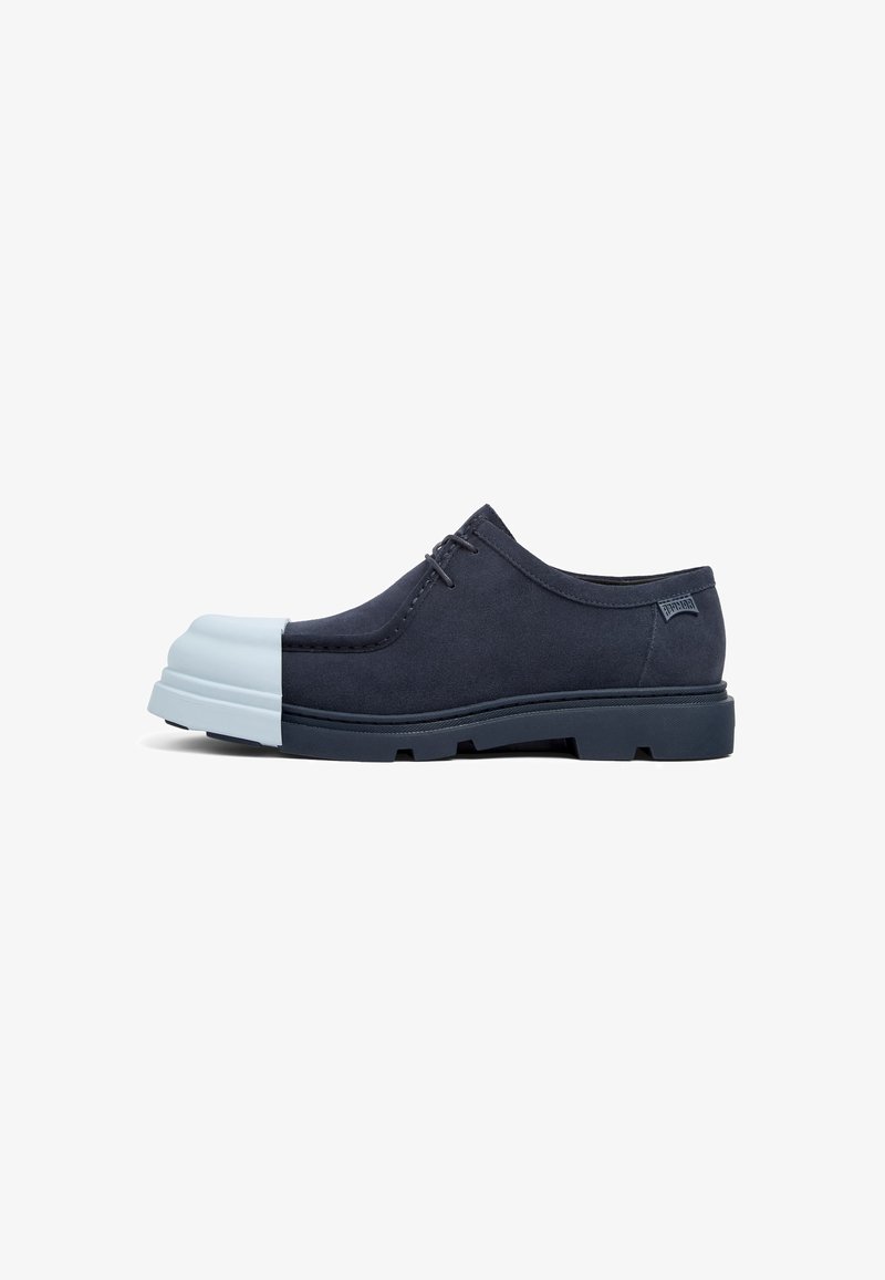 Navy suede shoe with a rubberized light blue toe cap. Features a low profile, round shape, and textured sole with visible treads.