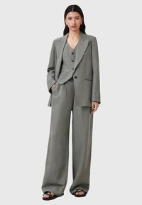Grijze linnen blazer en bijpassende wijde broek met een gestructureerde afwerking. De blazer heeft een ingezette kraag en dubbele knopen.