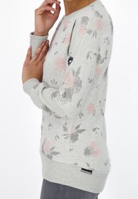 Light gray floral sweatshirt with pink and gray patterns, ribbed cuffs and hem, featuring a small logo on the left sleeve.