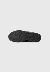 Semelle de basket noire avec une surface en caoutchouc texturé présentant un motif de semelle géométrique pour assurer l'adhérence. Design plat, sans aucune marque visible.