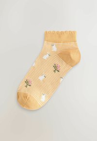 Žltá členková ponožka s bielymi vzormi zajaca a kvetov, s rebrovanou textúrou a vzorovaným volánovým lemom. Pruhované telo pridáva detaily.