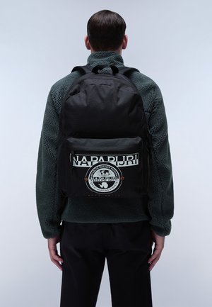 Sac à dos en tissu noir avec une grande poche avant, arborant un logo circulaire et du texte. Le design comprend des bretelles réglables et une texture douce.