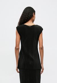 Μαύρη πλισέ μπλούζα με στρογγυλή λαιμόκοψη, κοντά μανίκια και υφή υφάσματος, διαθέτοντας ίσια γραμμή και διακριτές πλαϊνές σχισμές στο στρίφωμα.