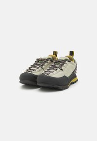 Světle šedé a černé turistické boty s gumovými podrážkami, barevnými tkaničkami a žlutými akcenty, které mají strukturovaný vršek a poutko na patě.