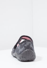 Svart slip-on skor med en strukturerad yta, mjuk rosa foder och en tjock gummisula. Har en böjd baksida och minimal branding.