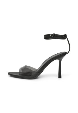 Sandale noire à talon haut avec bride transparente à l'avant et fine bride de cheville avec boucle argentée, présentée sur fond blanc.